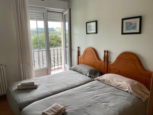 a bedroom with two beds and a large window at Ermita San Vicente de la Barquera Duplex in San Vicente de la Barquera