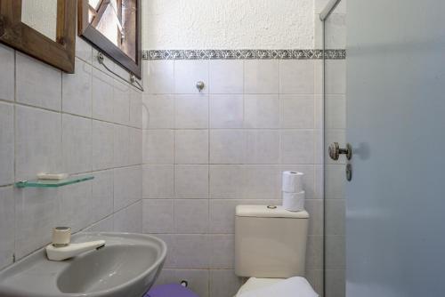 a white bathroom with a toilet and a sink at Pousada Y-Goá in Bertioga