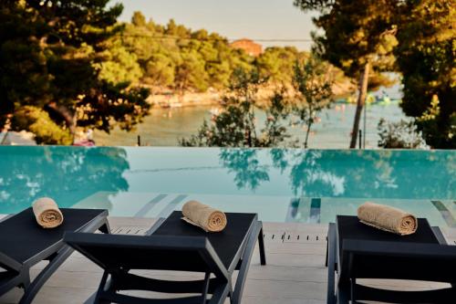 two black tables and chairs next to a swimming pool at Colentum Resort Murter in Murter