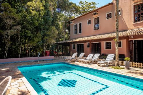 a swimming pool with chairs and a house at Pousada Y-Goá in Bertioga