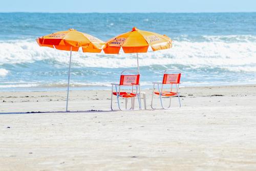 two chairs and two umbrellas on the beach at Pousada Y-Goá in Bertioga