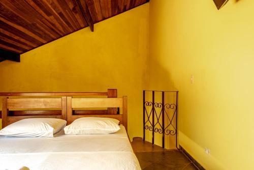 a bedroom with two beds in a yellow wall at Pousada Y-Goá in Bertioga