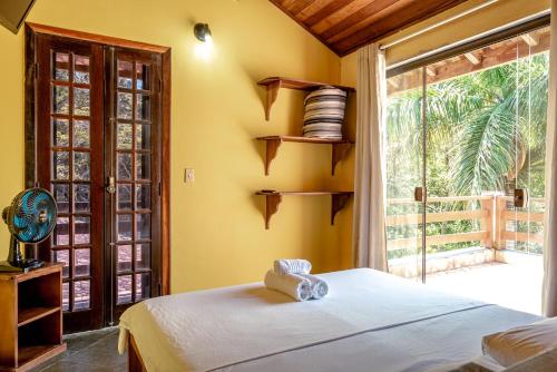 a bedroom with a bed and a large window at Pousada Y-Goá in Bertioga