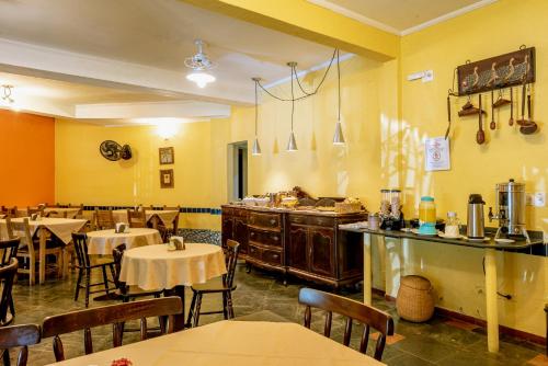 a restaurant with tables and chairs in a room with yellow walls at Pousada Y-Goá in Bertioga