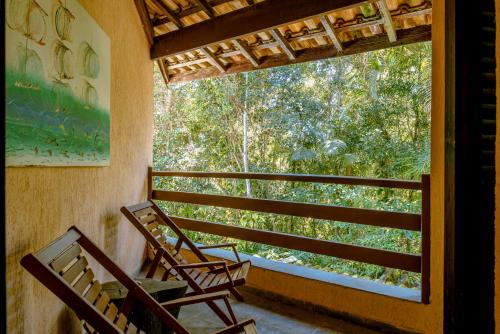 a screened in porch with two chairs and a window at Pousada Y-Goá in Bertioga