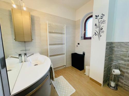 a white bathroom with a sink and a window at Casa Levante 4 in Cannobio