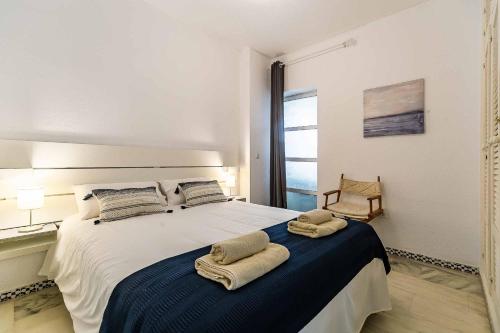 a bedroom with a large bed with two towels on it at Sur Suites Castillo in Fuengirola