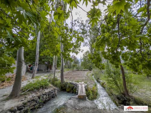 a bench in the middle of a river with trees at Ehsan-e-Bassi in Gilgit