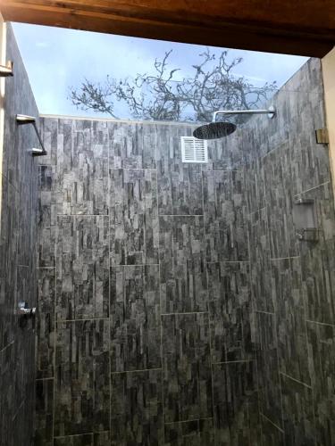 a bathroom with a shower with a stone wall at Voces de Aves Glamping in Chocontá