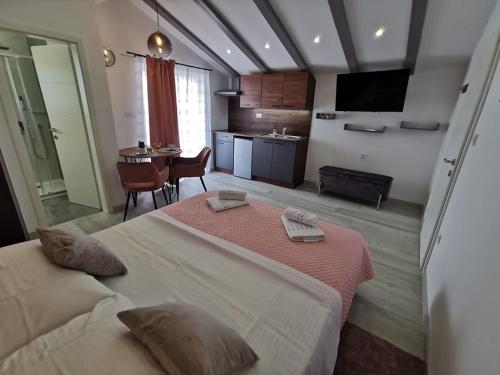 a bedroom with a large bed and a kitchen at New Nikolina 4 star in Mali Lošinj