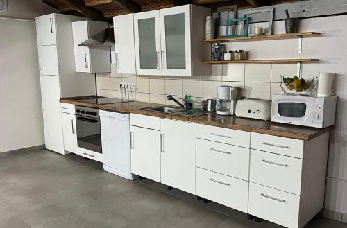 una cocina con armarios blancos y electrodomésticos blancos en B&B Home, en Sighişoara