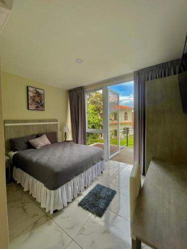 a bedroom with a bed and a large window at Hotel Finca San Nicolas in San Salvador