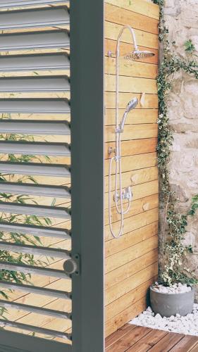 a shower in a bathroom with a wooden wall at Rector's Villa - Charming Retreat in Old Town with Jacuzzi in Private Courtyard in Rab