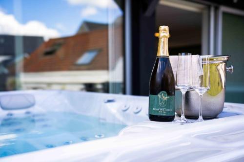 a bottle of champagne and two glasses on a tub at SPA & Garden - Luxury Private Apart' Mons Center in Mons