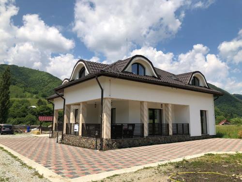 ein weißes Haus mit einem Dach auf einer steinernen Einfahrt in der Unterkunft Pensiunea Sofia in Telciu