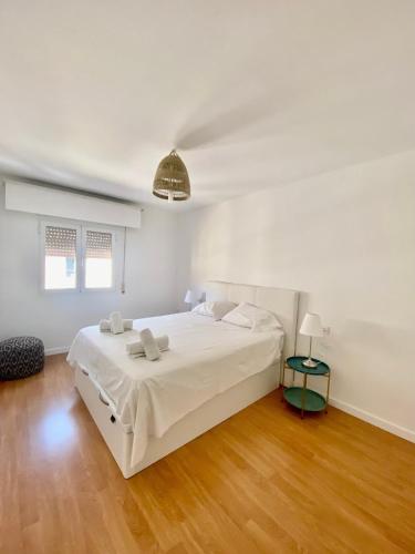 a white bedroom with a large white bed and wooden floors at Suite Homes Alamos Terrace in Málaga