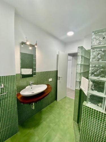 a green tiled bathroom with a sink and a mirror at Suite Homes Alamos Terrace in Málaga