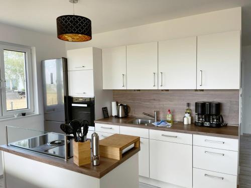 a kitchen with white cabinets and a sink at Exklusives Apartment mit Blick auf den See in Großräschen