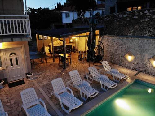 een groep stoelen en een zwembad in de nacht bij Villa Horizont Mostar in Mostar