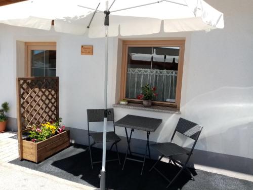 einen Tisch und Stühle unter einem Sonnenschirm auf einer Terrasse in der Unterkunft Appartment Paul in Alpbach