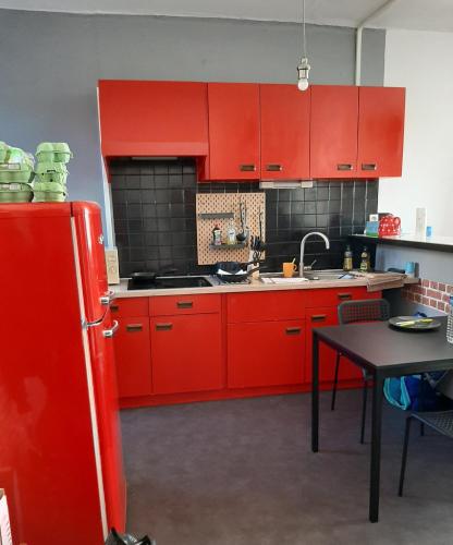 een keuken met rode kasten en een rode koelkast bij Appartement bord de vilaine, proche centre et gare in Redon