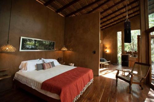 a bedroom with a bed and a chair in a room at OJO DE ÁRBOL, boutique cabin in the real jungle in Tulum