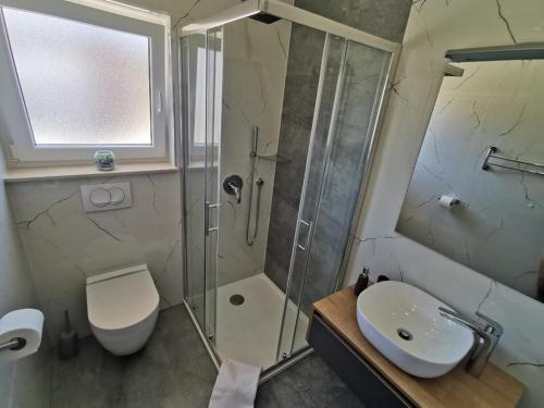 een badkamer met een douche, een toilet en een wastafel bij New Nikolina 4 star in Mali Lošinj