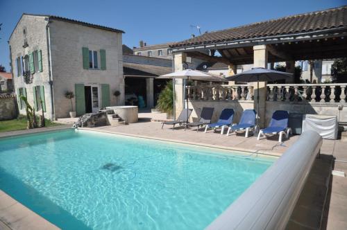 une piscine avec chaises et parasols sur un immeuble dans l'établissement Le Hangar, à Saint-Jean-dʼAngély