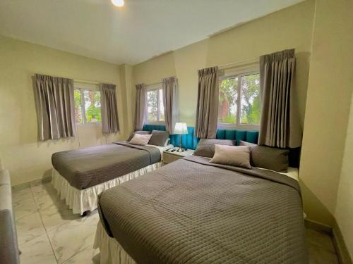 twee bedden in een kamer met twee ramen bij Hotel Finca San Nicolas in San Salvador
