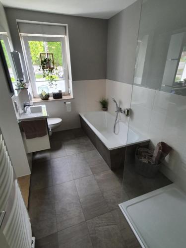 La salle de bains est pourvue d'une baignoire, d'un lavabo et d'une fenêtre. dans l'établissement Ferienhaus Dani, à Bad Frankenhausen