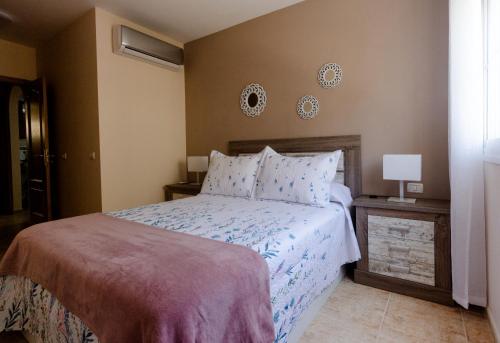 a bedroom with a bed and a lamp on a table at Apto ACHE, acogedor apartamento de 66 m con terraza, aire acondicionado y parking privado gratuito in Los Abrigos