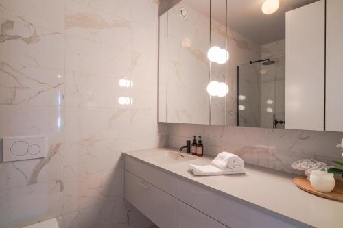 a white bathroom with a sink and a mirror at Ocean Breeze Luxury Apartment in Reykjavík