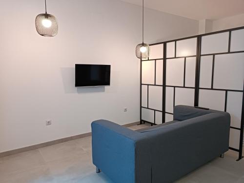 sala de estar con sofá azul y TV en APARTAMENTOS LOS GUINDOS, en Málaga