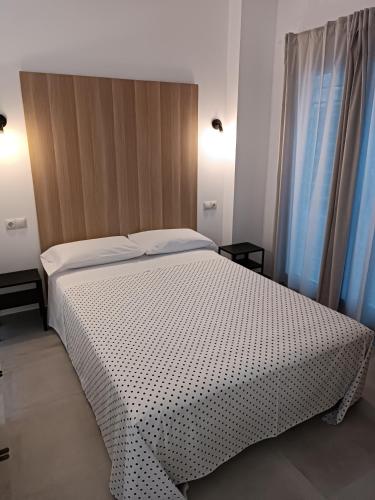 a bedroom with a white bed and a window at APARTAMENTOS LOS GUINDOS in Málaga
