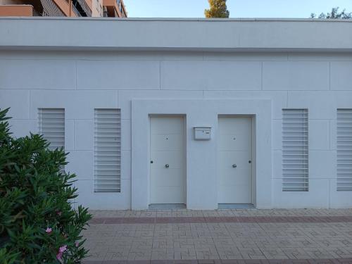 un edificio blanco con tres puertas. en APARTAMENTOS LOS GUINDOS, en Málaga