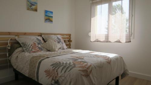 een slaapkamer met een bed met een dekbed en een raam bij Appartement chaleureux et élégant en résidence. in Labastidette