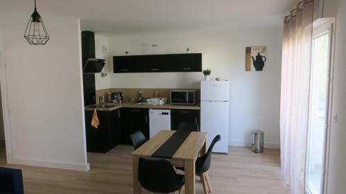 een keuken met een tafel en een witte koelkast bij Appartement chaleureux et élégant en résidence. in Labastidette