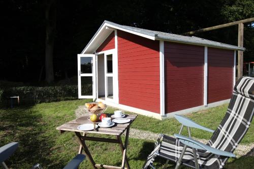 einen roten und weißen Schuppen mit einem Tisch und Stühlen in der Unterkunft Ostseecamp Lübecker Bucht Wanderhütte in Scharbeutz