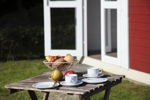 einem Holztisch mit einer Schale Obst, Tassen und Teller in der Unterkunft Ostseecamp Lübecker Bucht Wanderhütte in Scharbeutz