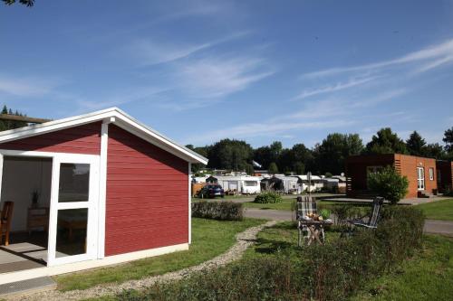 einen roten Schuppen mit einem Tisch im Hof in der Unterkunft Ostseecamp Lübecker Bucht Wanderhütte in Scharbeutz