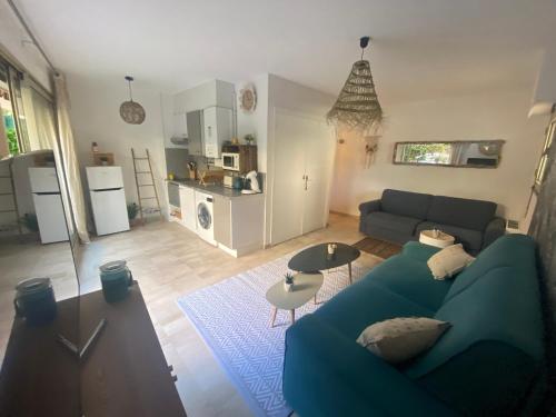 un salon avec un canapé bleu et une cuisine dans l'établissement La Beau'M Juan Les Pins centre ville 200m de la mer terrasse et jardin, à Juan-les-Pins