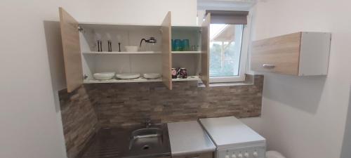 una pequeña cocina con fregadero y ventana en Lali Apartman, en Balatonudvari