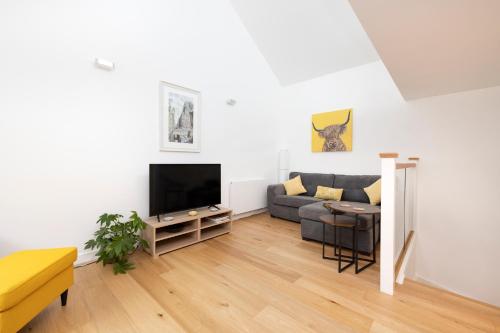 a living room with a couch and a tv at Edinburgh Modern 3-Storey 3-Bedroom City Apartment in Edinburgh