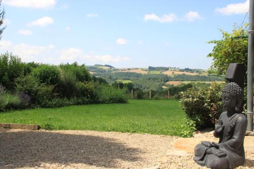a statue of a buddha sitting on the ground at La Vieille Grange avec piscine et jardin in Prévinquières