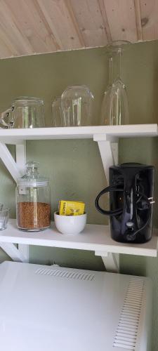 a kitchen shelf with glass dishes and a toaster at Cosy private cottage with stunning view in Sunne