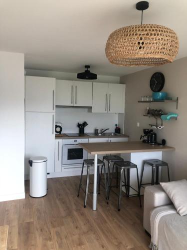 una cucina con mobili bianchi, un tavolo e sgabelli di Les Bains de Wimereux a Wimereux