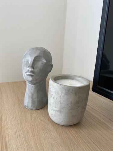 a statue of a head sitting next to a cup at Lovely Sea View 3 Bedroom Apt in Marsalforn Gozo. in Żebbuġ