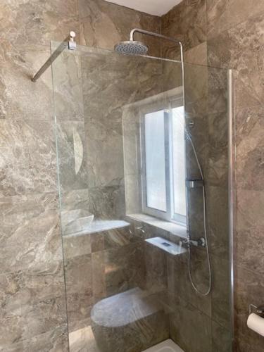a bathroom with a shower with a toilet and a window at Lovely Sea View 3 Bedroom Apt in Marsalforn Gozo. in Żebbuġ