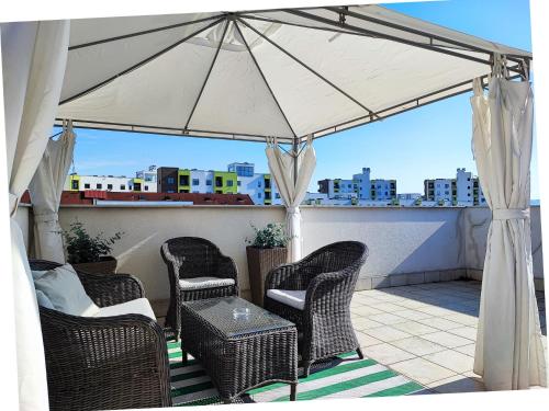 um pátio com cadeiras e um guarda-sol no telhado em FilinHome Dusana 3-bedroom Suite em Novi Sad