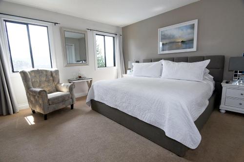 a bedroom with a large bed and a chair at A Touch of English B&B in Kelowna